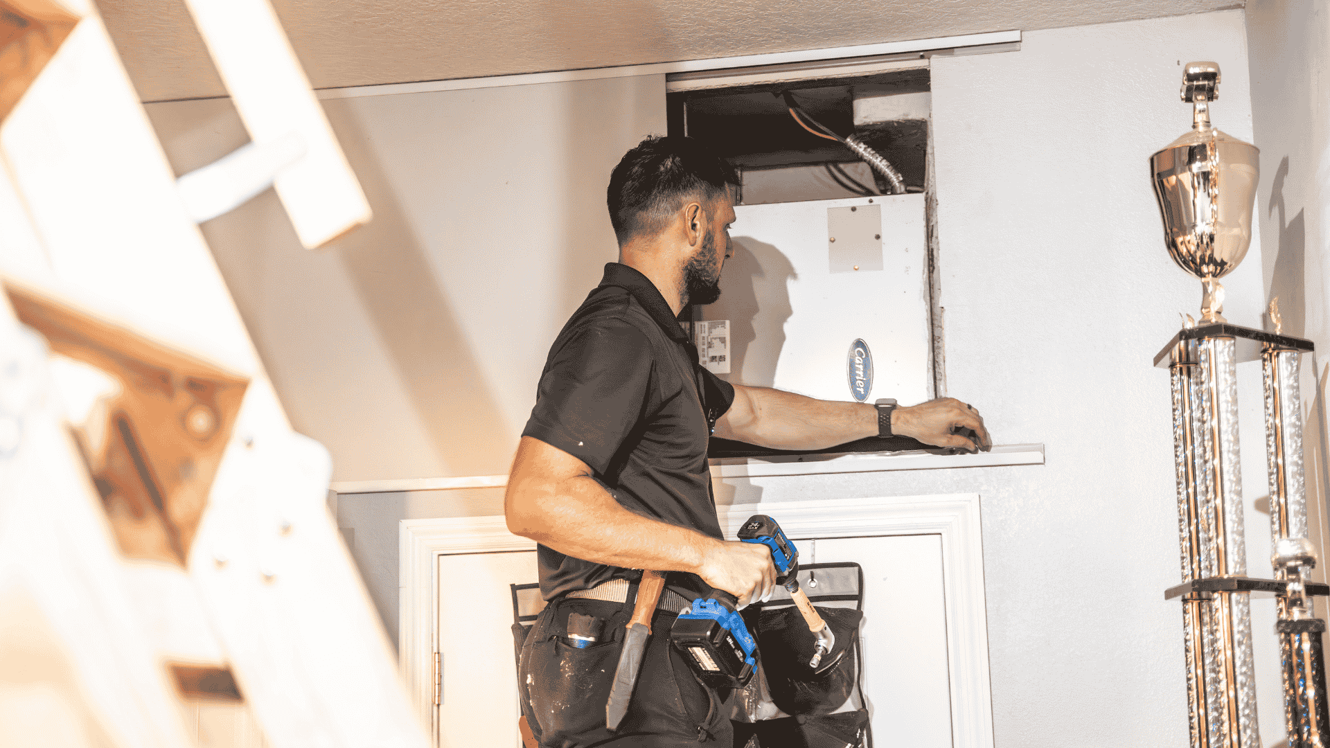 An Air Titans technician uses a cordless drill to service the interior of a home’s HVAC unit in a utility closet.