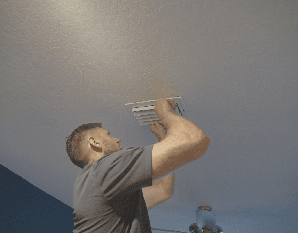 Air Titan specialist adjusting ceiling vent for air conditioning system in a Tampa residence