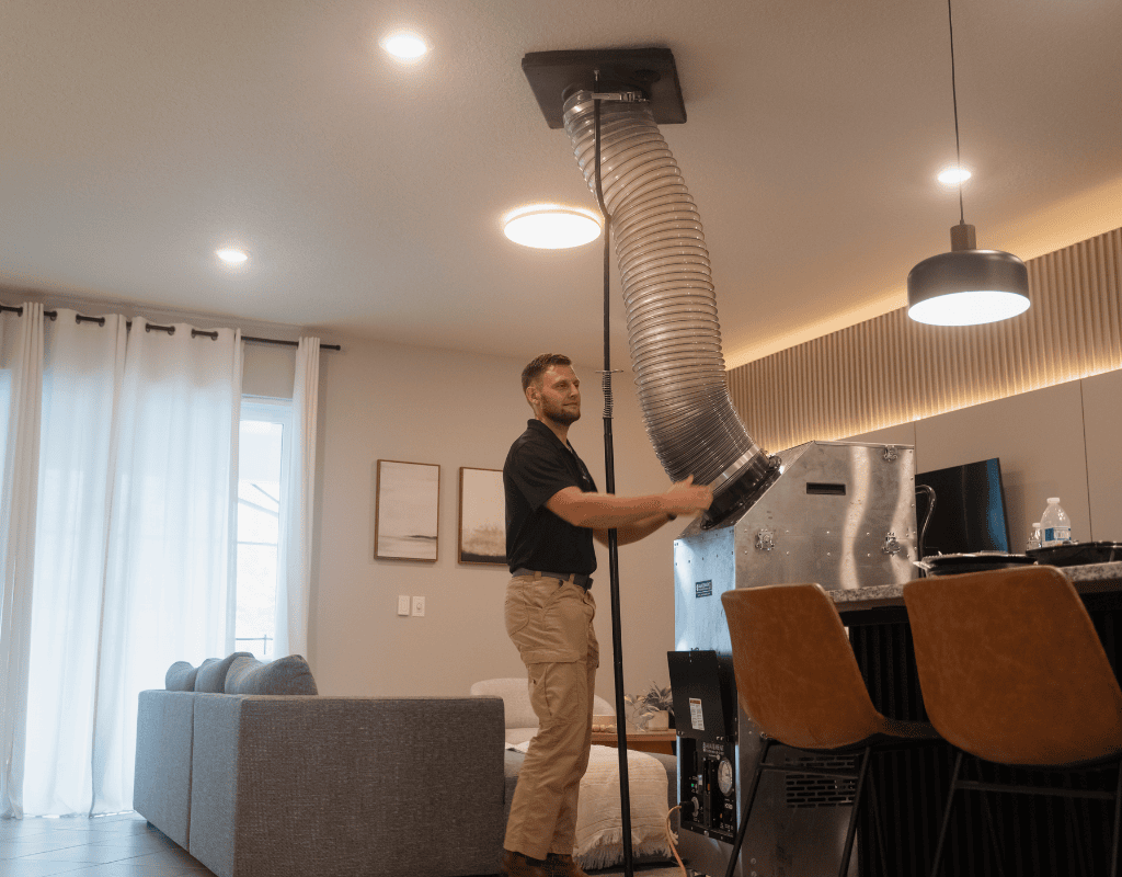 Air Titans crew member connecting high-powered vacuum hose for dryer vent cleaning in Tampa
