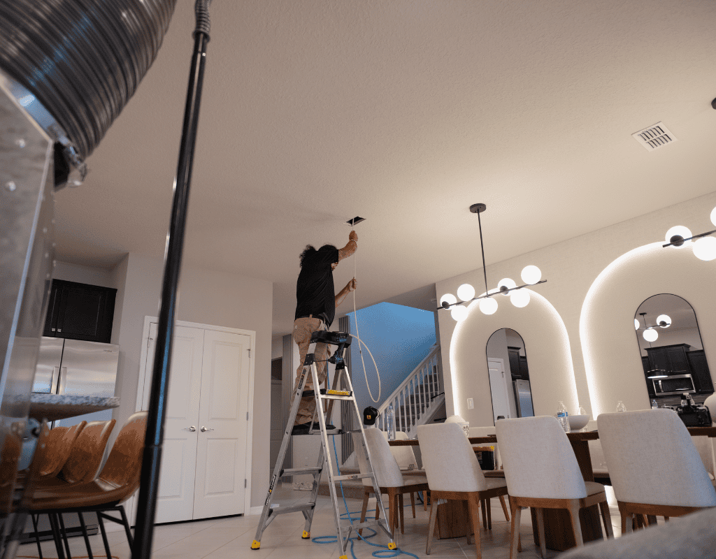 Air Titan technician installing UV light system inside ceiling duct in a Tampa residence